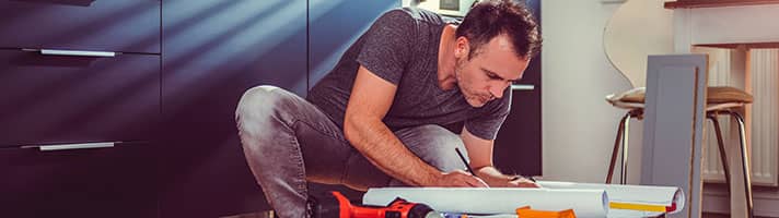 Workman writing on paper with tools around him.
