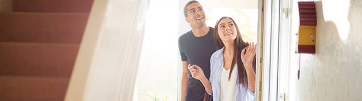 Man and woman entering a house looking excited.