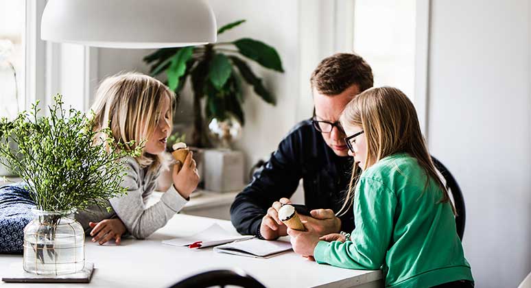 Family at the dining table all looking at a mobile phone.