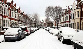 Snow covered street with parked cars.